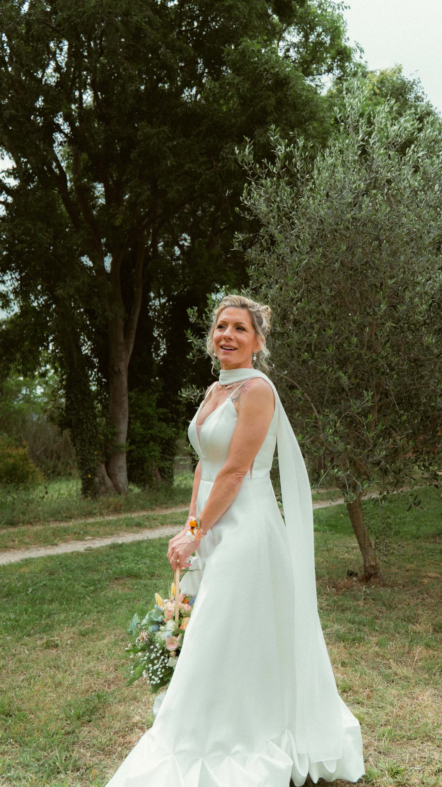 Portrait de la mariée en robe blanche, oliviers, regard spontané